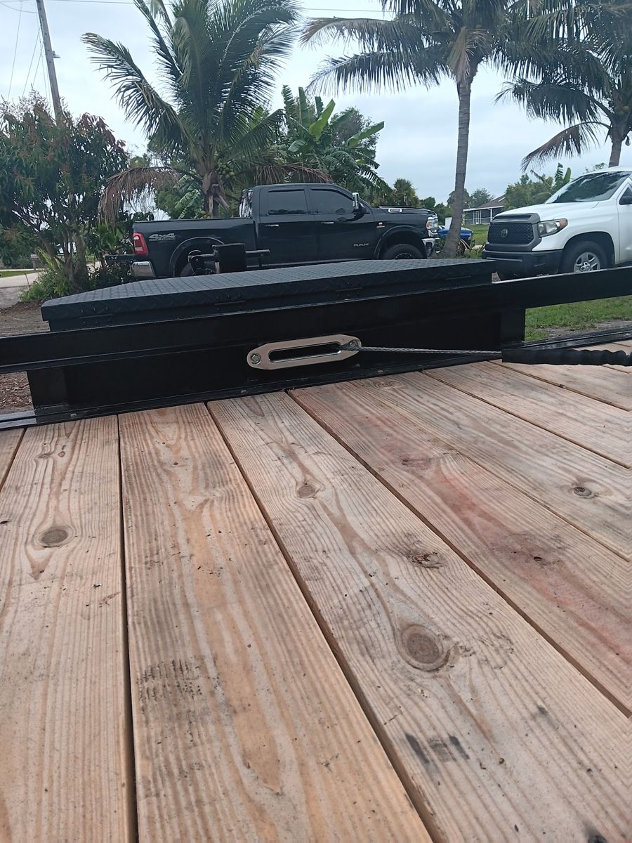 Wooden truck bed deck with a black tool-box rail, trucks in the background